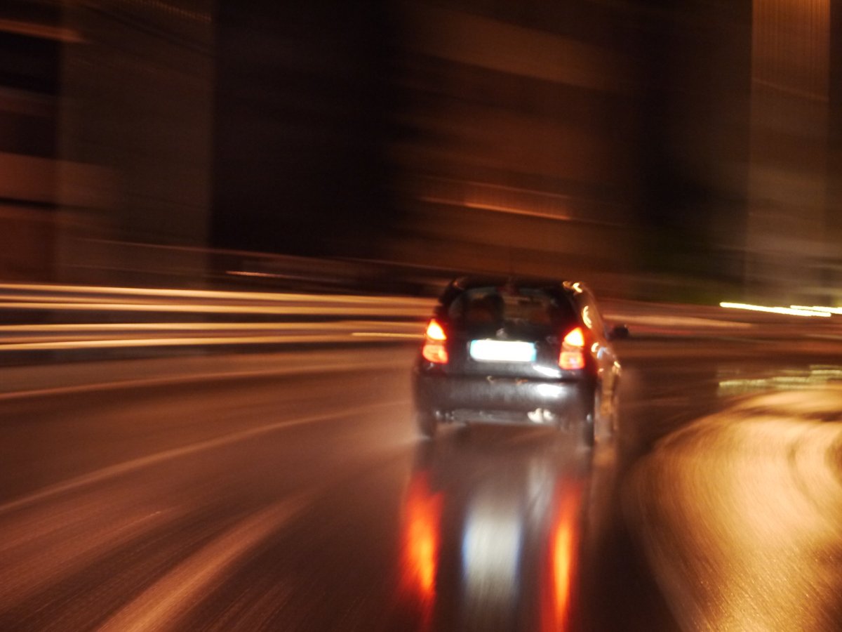 Car driving down a wet road at night with lights on